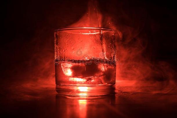 玻璃关于威士忌酒和冰向木制的表面和颜色光和