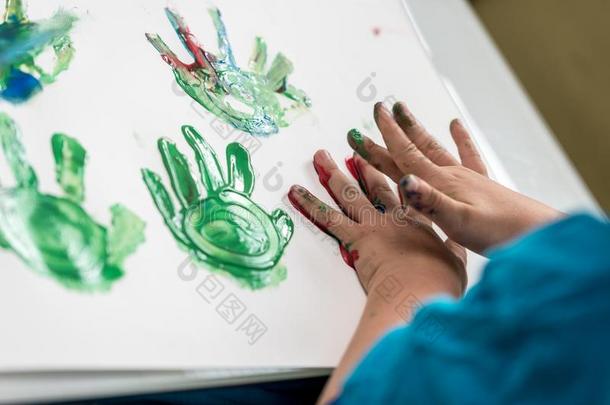 男孩绘画和他的手制造富有色彩的手掌照片
