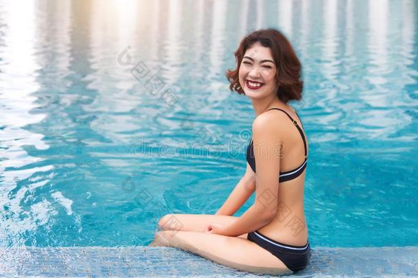 幸福的亚洲人女士微笑的向照相机和比基尼式游泳衣