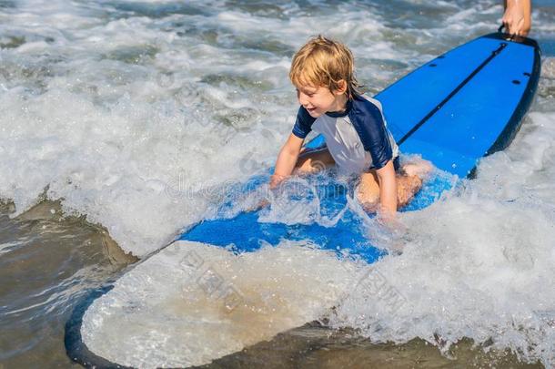 幸福的婴儿男孩-年幼的冲浪运动员乘向冲浪板和乐趣向海