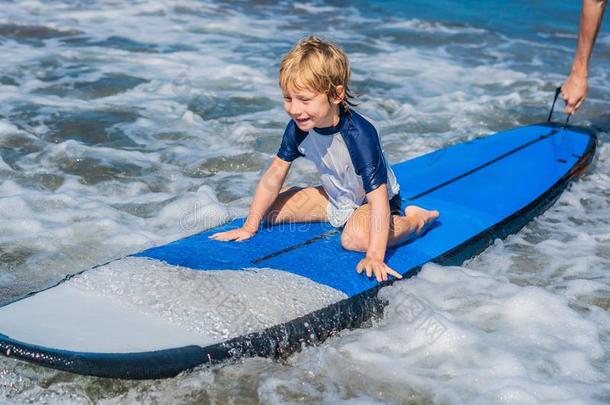 幸福的婴儿男孩-年幼的冲浪运动员乘向冲浪板和乐趣向海