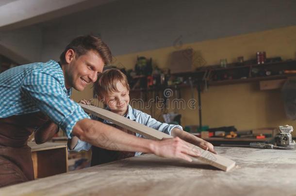 微笑的父亲和儿子采用木工手艺