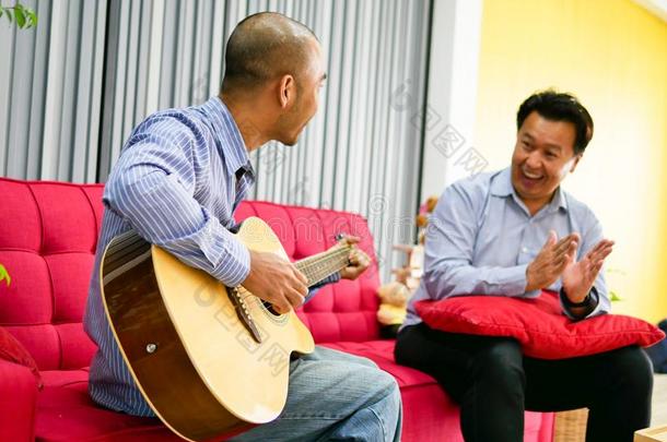两个亚洲人家伙是演奏吉他,音乐仪器为幸福的一