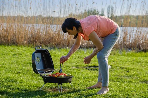 女人做barbecue<strong>吃</strong>烤烧肉的野餐烤腌<strong>羊肉</strong>串向烧烤和肉和蔬菜.夏
