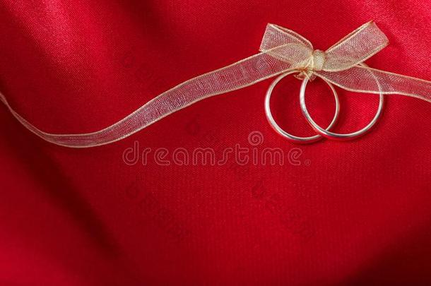 两个金色的婚礼戒指系和一金色的带向红色的s一tin