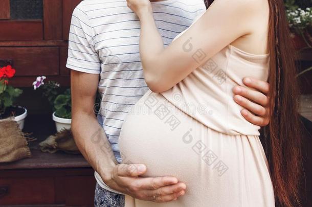 怀孕的女人和大的肚子碰撞热烈地拥抱和她丈夫.偶然