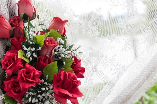 红色的玫瑰花束和白色的蕾丝窗帘