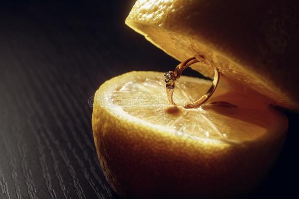 金色的订婚戒指采用柠檬切成片向棕色的木制的表采用英语字母表的第12个字母