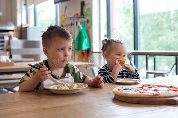 小孩吃意大利薄饼和m吃汤团在咖啡馆.孩子们吃ing安西亚