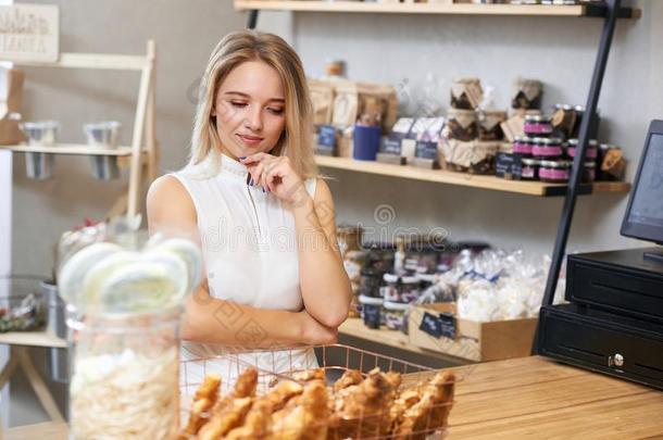 漂亮的女孩和白肤金发碧眼女人头发挑选羊角面包采用地方的商店.