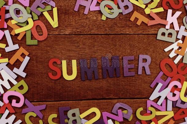 富有色彩的木制的字母表夏拼写向木制的背景