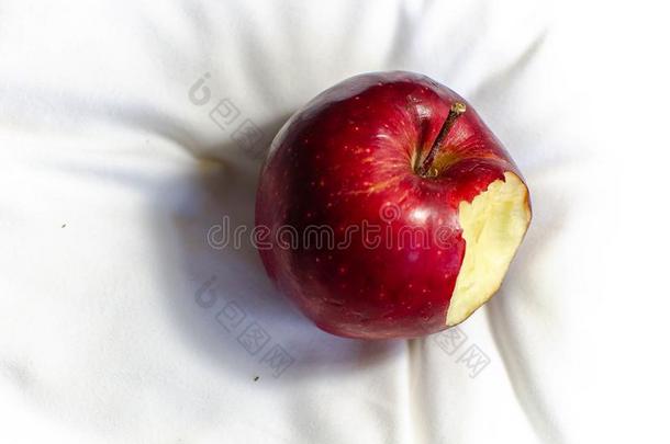 咬红色的苹果向一白色的纺织品b一ckground