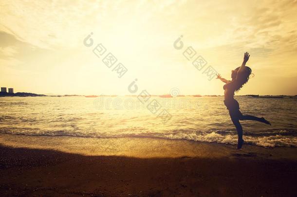 幸福的亚洲人女人用于跳跃的向指已提到的人海滩