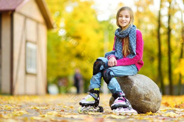 漂亮的小的女孩学问向滚筒溜冰向美丽的秋