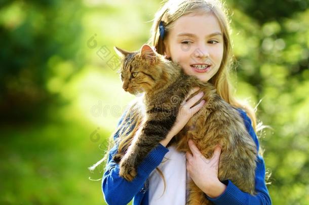 漂亮的小的女孩和她猫向和煦的：照到阳光的秋一天.值得崇拜的children儿童