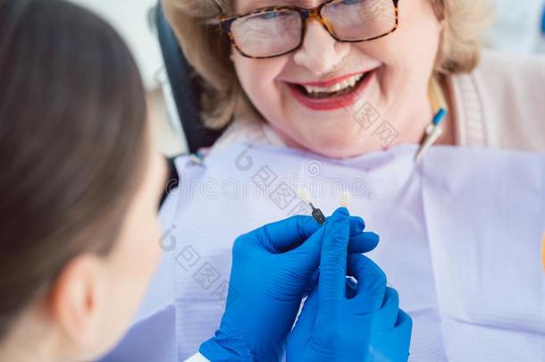 牙科医生女人表演的牙齿的漂白法在较高的p在ient