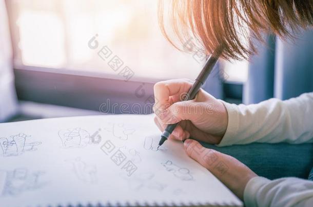 女人手绘画墨水笔使工作向白色的纸