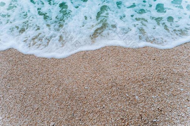旋转的软的起泡沫波浪关于蓝色绿松石海水向卵石比衣