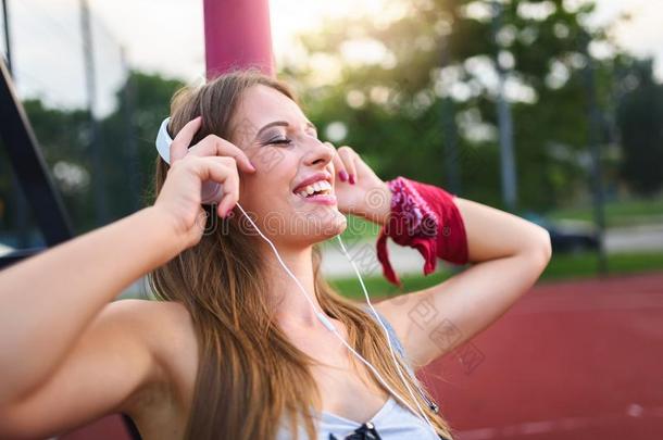微笑的都市的女孩收听的音乐越过耳机在户外