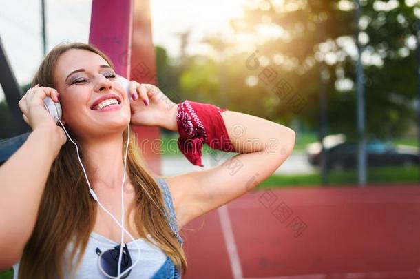 微笑的<strong>都市</strong>的女孩收听的<strong>音乐</strong>越过耳机在户外