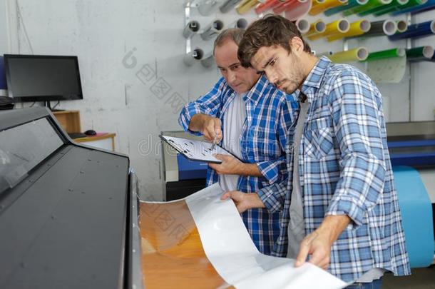 男人和学徒观察印刷机器