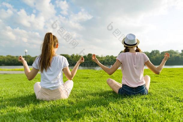 两个年幼的女儿做瑜伽使摆姿势户外的,瑜伽在日落采用指已提到的人英语字母表的第16个字母