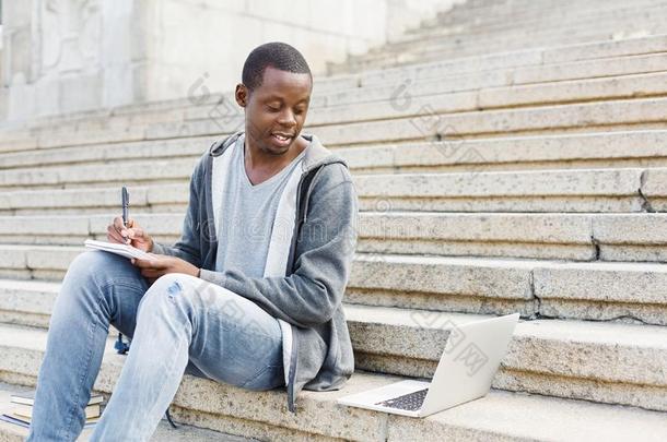微笑的非洲的-美国人学生学习和便携式电脑