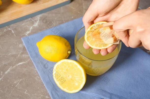 女人挤压柠檬果汁和钻孔器进入中玻璃