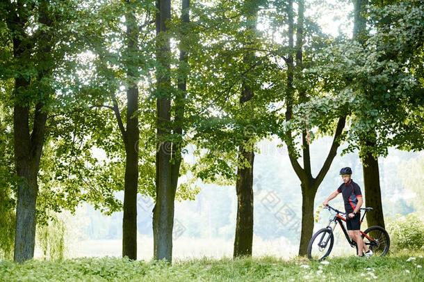 骑自行车的人起立在近处自行车经过绿色的美丽的树