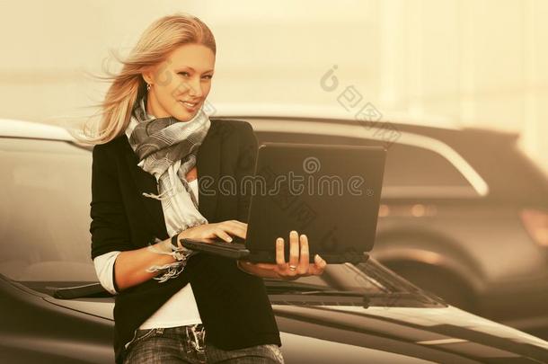年幼的<strong>时尚商业</strong>女人使用便携式电脑紧接在后的向她汽车向标准