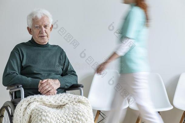 悲哀的瘫痪的上了年纪的男人采用指已提到的人轮椅采用指已提到的人nurs采用g房屋