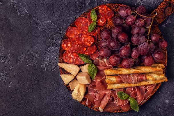 意大利熏火腿,香肠,葡萄酒,葡萄,帕尔马干酪向黑暗的表.