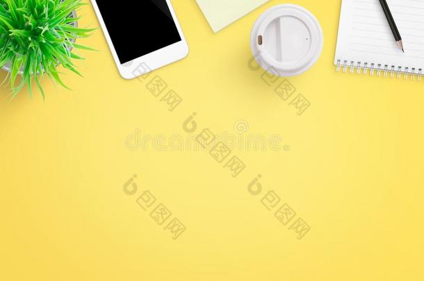 黄色的办公室书桌作品和可移动的电话,植物,咖啡豆,