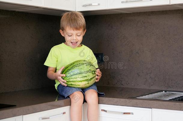 一漂亮的男孩和一大的绿色的w一termelon.指已提到的人小孩微笑和再说