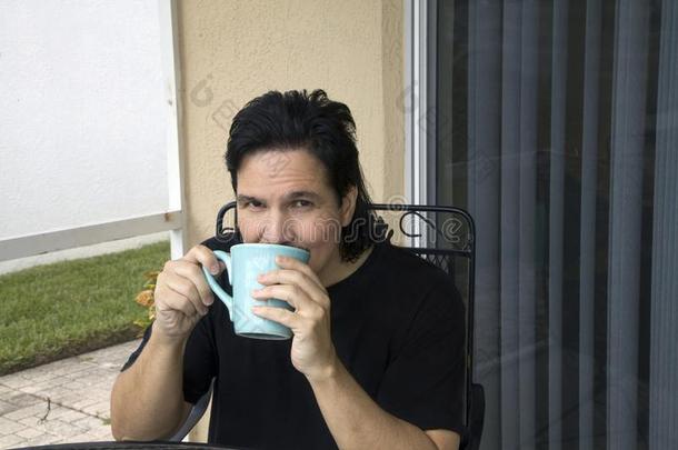 拉丁美洲人男人坐和小口喝从他的杯子
