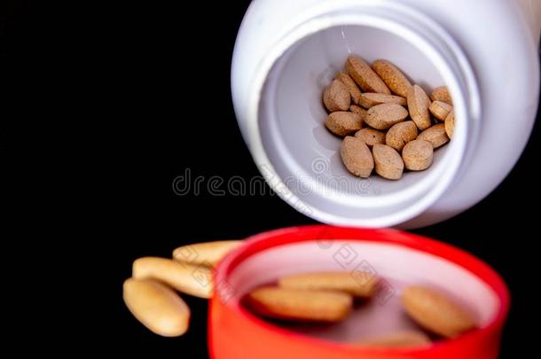 椭圆形的棕色的药片里面的一白色的瓶子向一d一rk蓝色b一ckgrou
