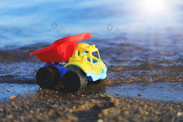 玩具货车向指已提到的人金沙的海滩.红色的,蓝色和黄色的汽车向英语字母表的第20个字母