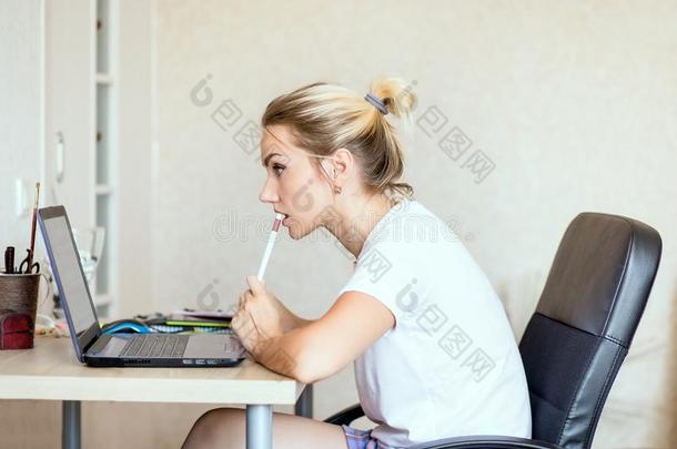 美丽的白肤金发碧眼女人女人工作的向便携式电脑在家.她是（be的三单形式思想