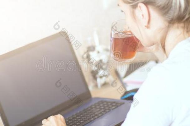 美丽的白肤金发碧眼女人女人工作的向便携式电脑在家和喝饮料全音节的第七音