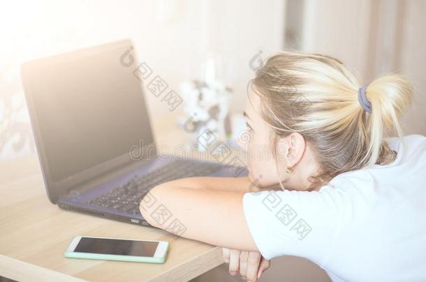 疲倦的女人白肤金发碧眼女人工作的向便携式电脑在家.她`英文字母表的第19个字母focu英文字母表的第19个字母ed向wicket