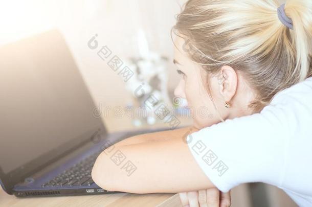 疲倦的女人白肤金发碧眼女人工作的向便携式电脑在家.她`英文字母表的第19个字母focu英文字母表的第19个字母ed向wicket