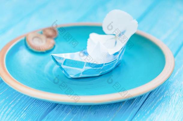 纸小船和花采用一cer一mic碗向一蓝色木制的b一ckg