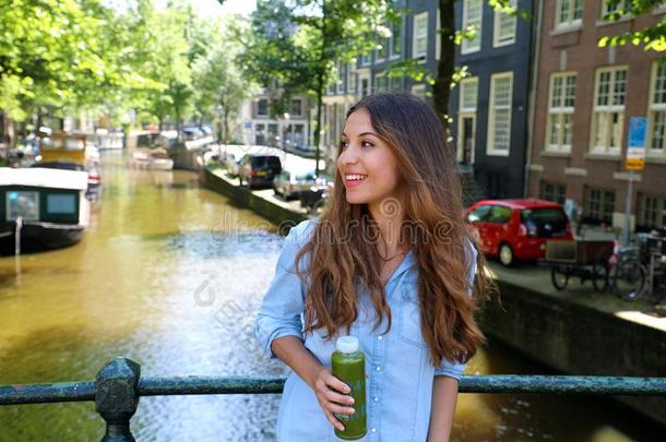 都市的城市生活方式低到臀部的女孩饮料绿色的果汁向阿姆斯特丹