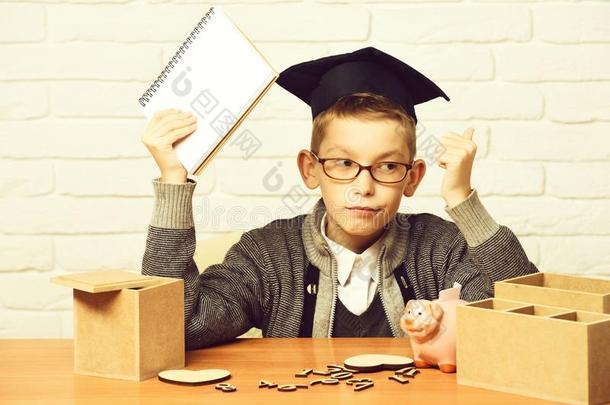 年幼的漂亮的学生男孩采用灰色的毛衣和眼镜sitt采用g在书桌