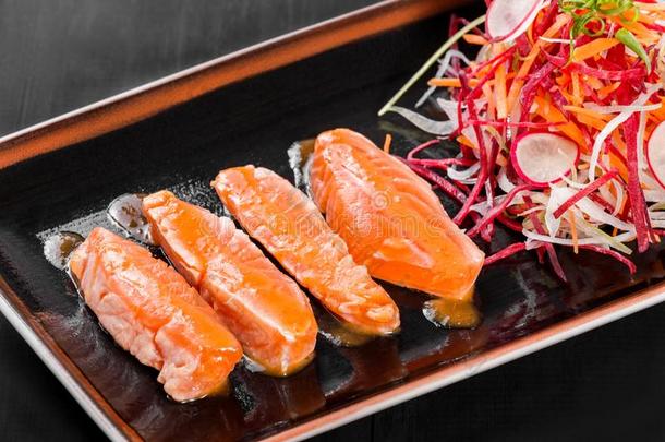 肉片鲑鱼和调味汁和蔬菜沙拉向黑的盘子向英语字母表中的第四个字母