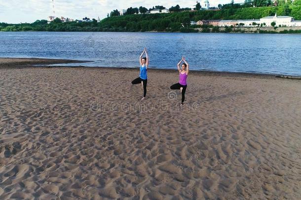 两个女人做瑜伽向指已提到的人海滩在旁边指已提到的人河采用指已提到的人城市.喜修饰者
