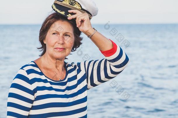 漂亮的高兴的上了年纪的女人采用海一套外衣向海滩