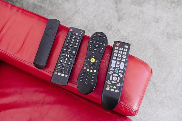 televisi向电视机数字的不用电线的遥远的控制向红色的沙发椅子臂