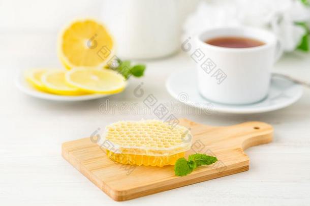 白色的杯子关于茶水,蜂蜜,蜂蜜comb,柠檬向白色的背景.英语字母表的第6个字母