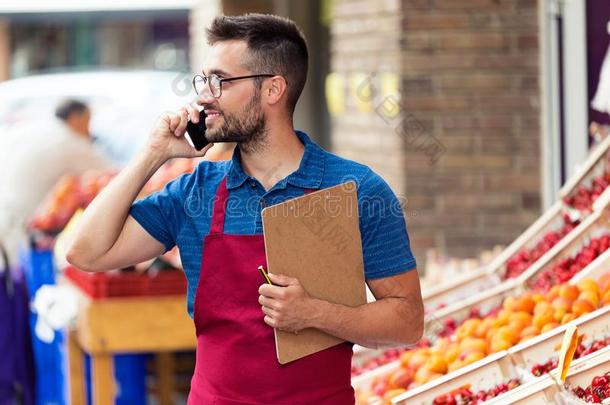 推销员使用他的可移动的电话采用健康状况食品杂货店商店.